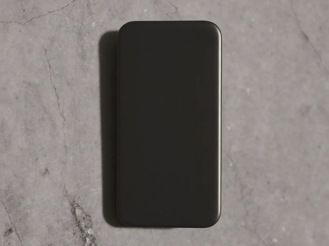 Slankt mat telefoncover på lys grå stenoverflade i sidelys
