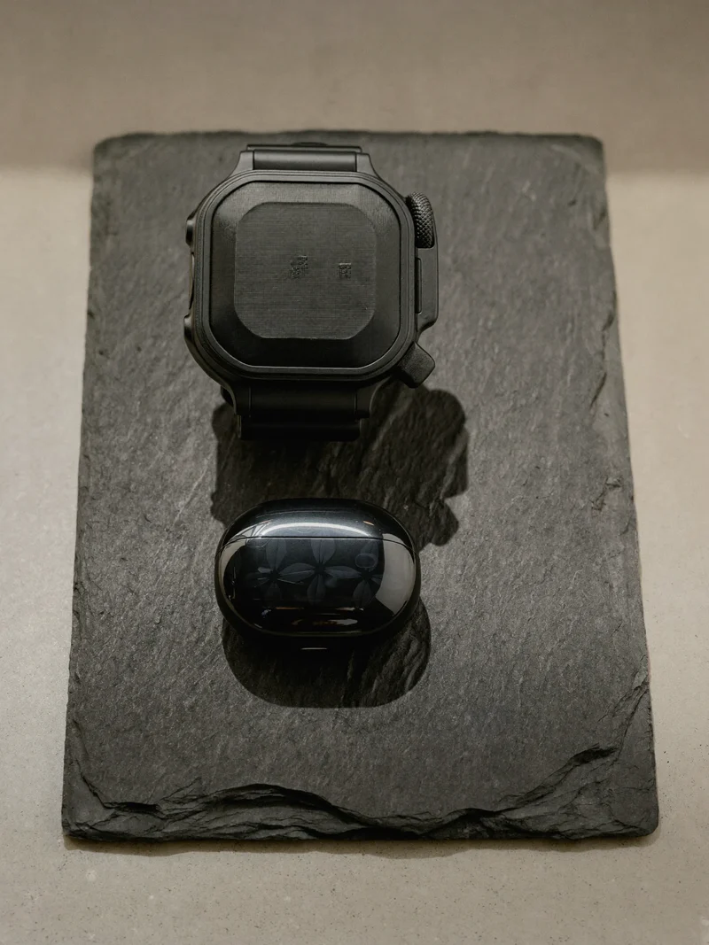 Robuste etuier til smartwatch og ørepropper på en skiferbakke
